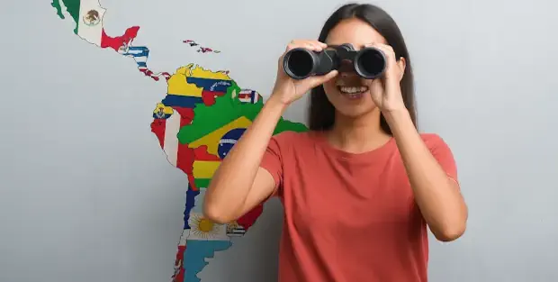 Joven con binoculares mirando hacia el mundo frente a un mapa de Sudamérica